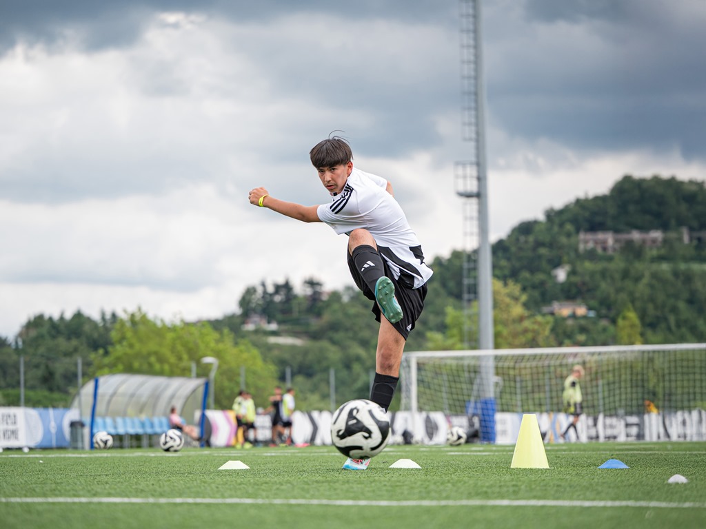 Giovane ragazzo che calcia il pallone allo Juventus Training Camp di Cantalupa